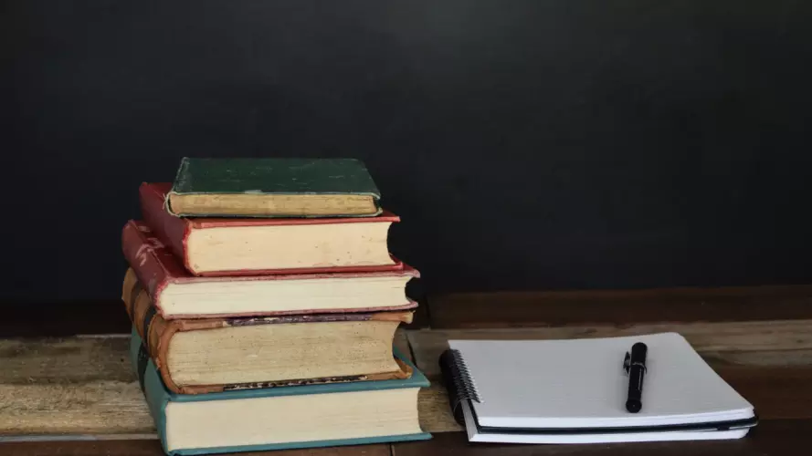 A pile of books next to a notebook
