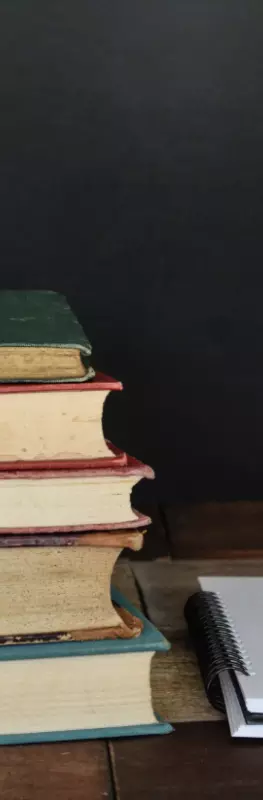 A pile of books next to a notebook