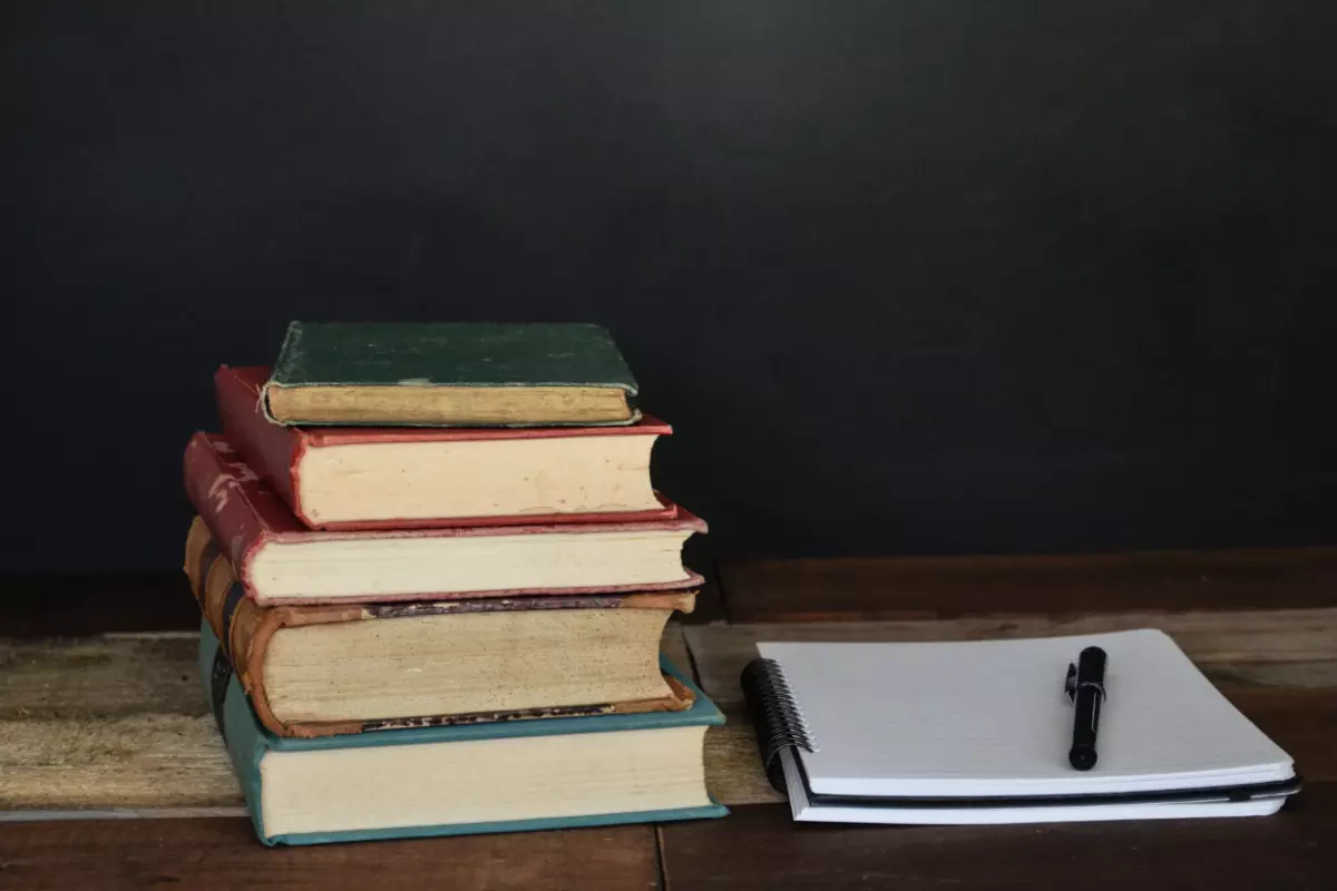 A pile of books next to a notebook